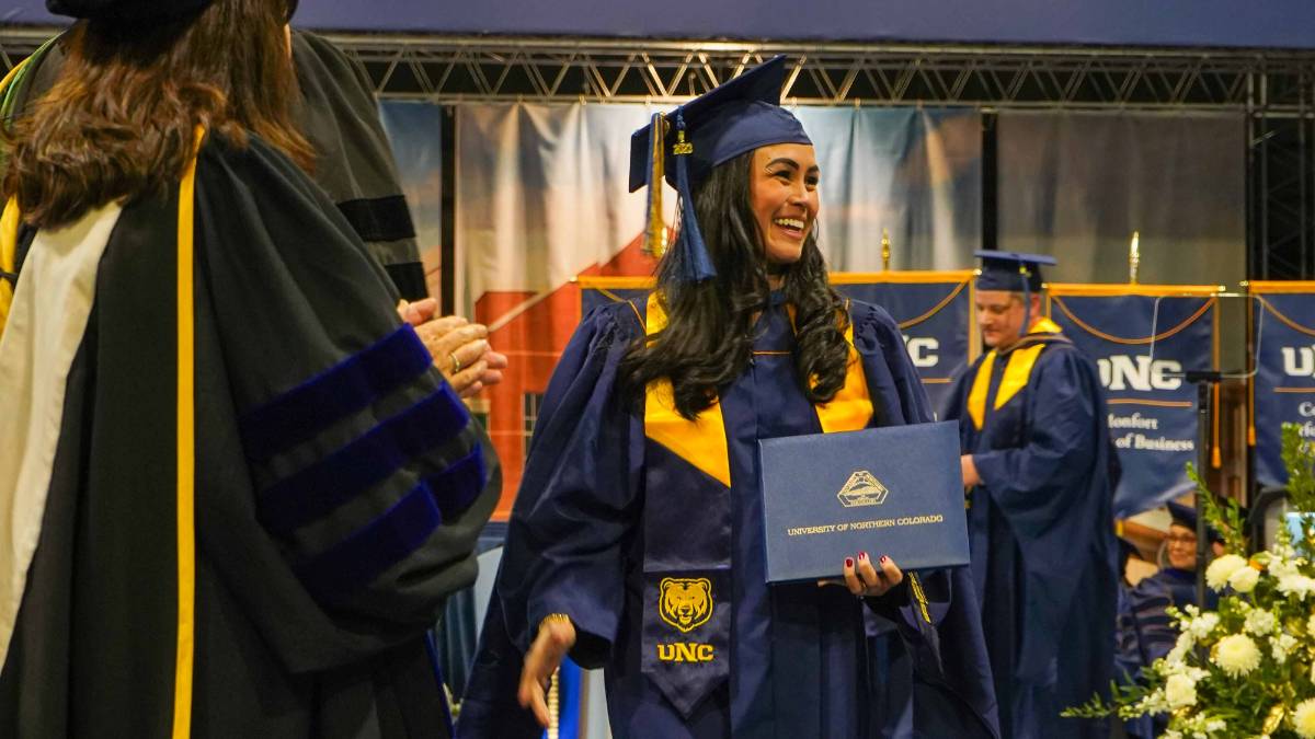 Female MBA graduate student smiling with diploma at commencement