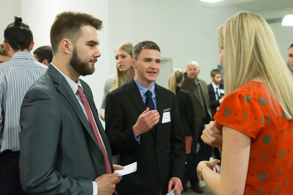 Students in professional business attire speaking with a business professional